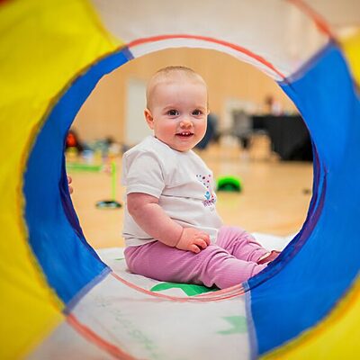 baby looking through a soft play tunnel