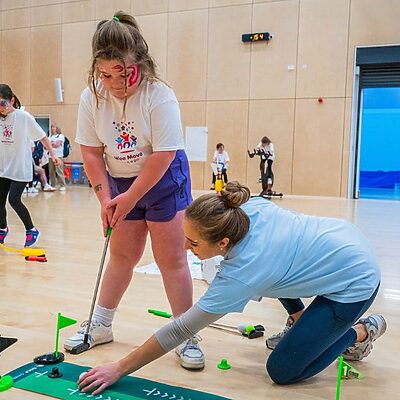 staff helping a participant with mini golf