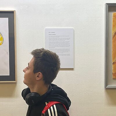 a young adult renal patient in front of their artwork as part of their my journey exhibition