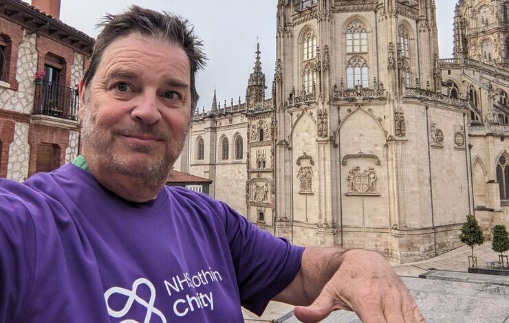 Alan McEwan walking the Camino de Santiago smiling for the camera in his NHS Lothian Charity t-shirt