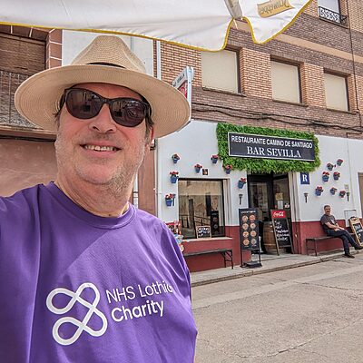 Alan McEwan walking the Camino de Santiago smiling for the camera in his NHS Lothian Charity t-shirt