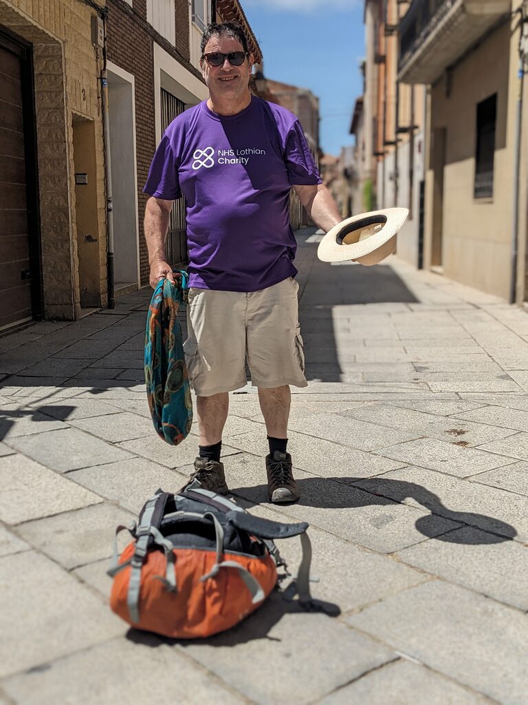 Alan McEwan walking the Camino de Santiago smiling for the camera in his NHS Lothian Charity t-shirt