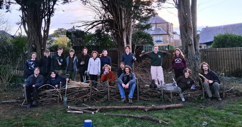 A group of volunteers in front of a tree smiling towards the carmera