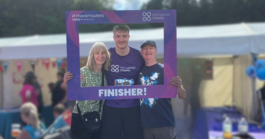 Alexander Ferguson at the finish line of the Edinburgh Marathon Festival standing beside his parents holding a Finisher frame