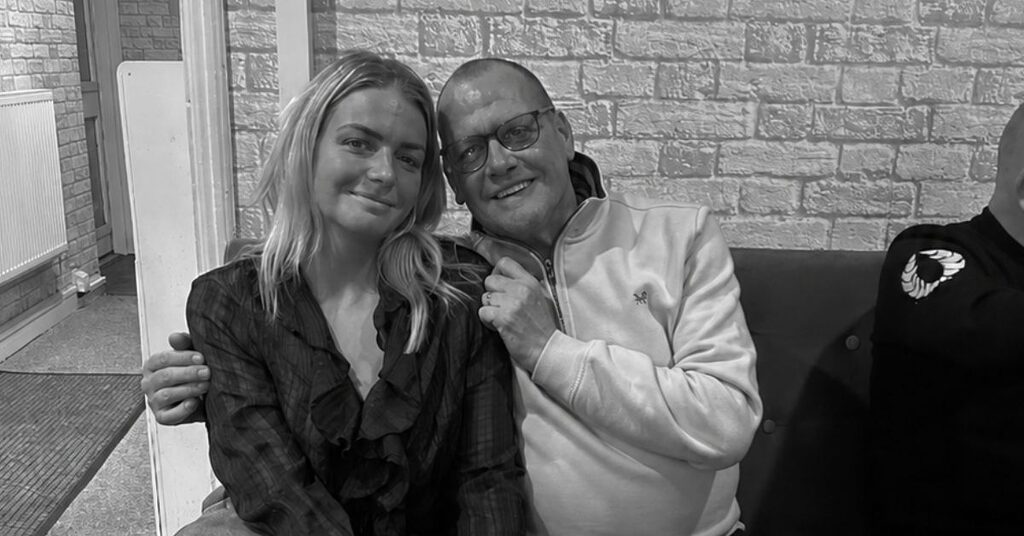 A black and white photo of Carly and her dad smiling at the camera