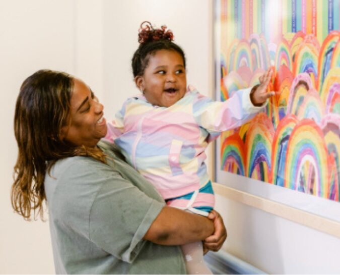 Lady holding her daughter looking at art