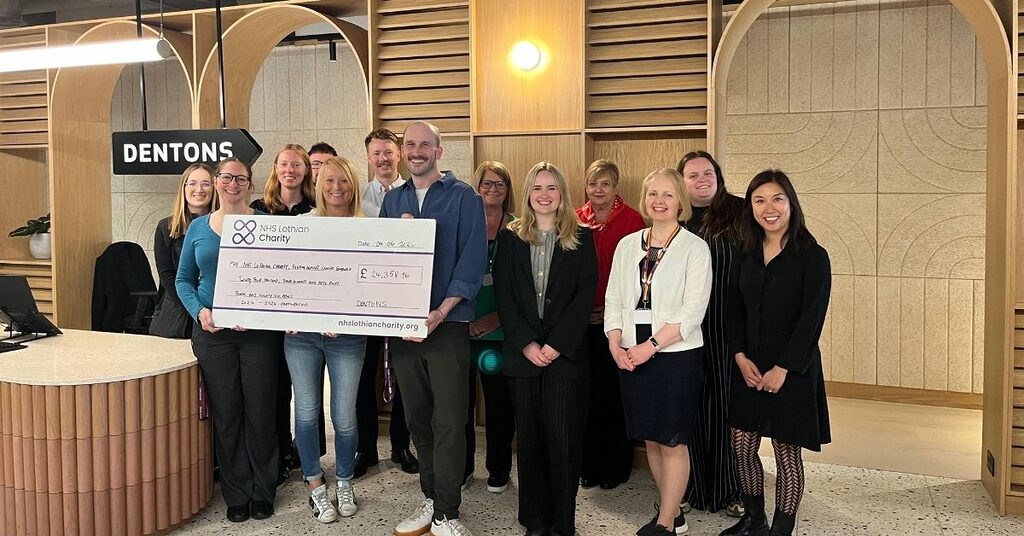 staff from dentons holding a large cheque