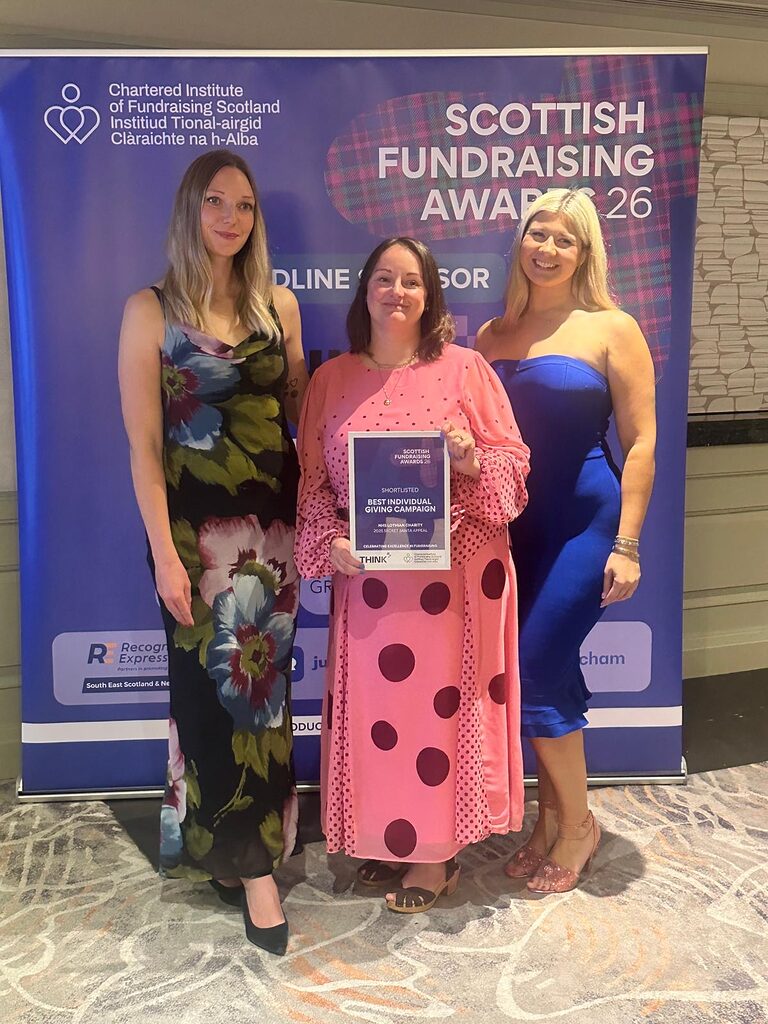 three members of the NHS Lothian Charity fundraising team holding up their runners up plaque in front of a Scottish Fundraising Awards banner
