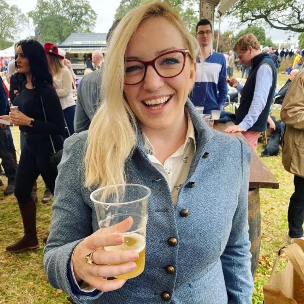 Babs Mackenzie holding a drink and smiling at the camera